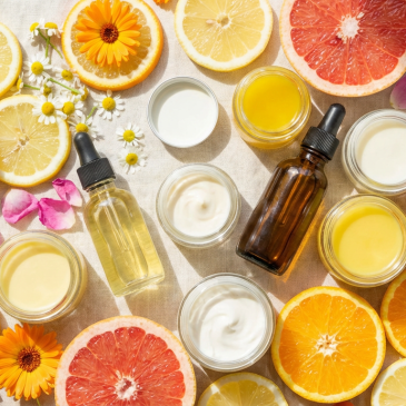 Flat lay of natural skincare jars and bottles surrounded by citrus slices and flowers.